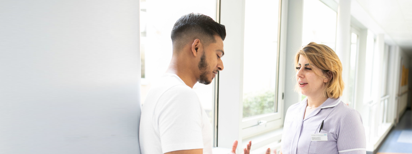 A man talking to a nurse in a hospital corridor