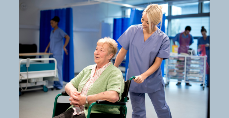 Healthcare staff pushing patient in a wheelchair as they leave hospital
