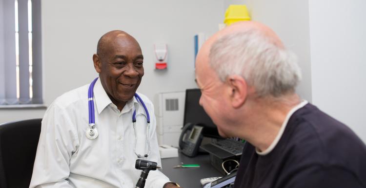 GP sitting opposite a patient about to take their tempreature GP sitting opposite a patient about to take their tempreature