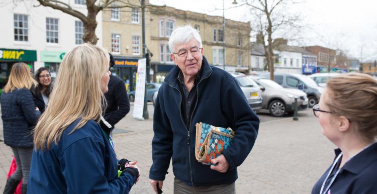 A man with a walking stick talking with some women