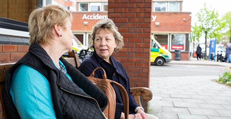 two ladies sit and talk on a bench two ladies sit and talk on a bench