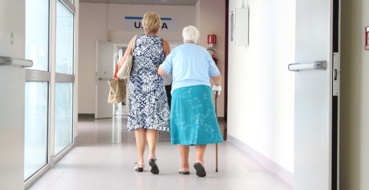 woman assisting an elderly lady in a hospital corridor