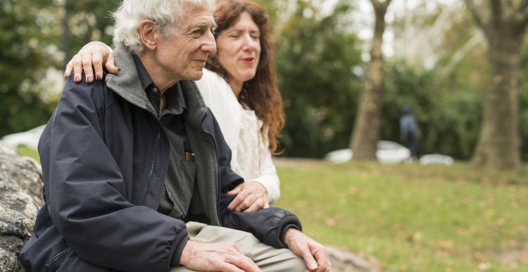 Elderly person sitting on a bench with a friend.