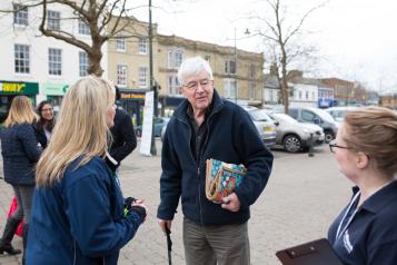 A man with a walking stick talking with some women