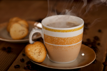 A cup of coffee with a biscuit