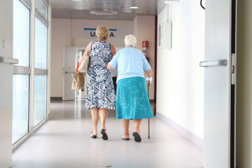 woman assisting an elderly lady in a hospital corridor
