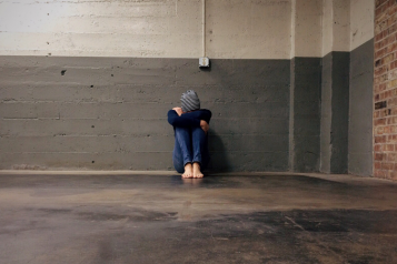 person sitting on the floor, head resting on knees