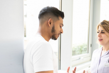 A man talking to a nurse in a hospital corridor