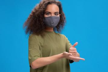 a person signing help in British Sign Language in a mask